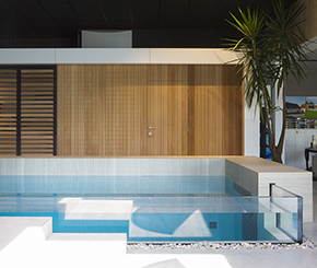 Design binnenzwembad in beton met glazen wand, hoogwaardige afwerkingsmaterialen en zwevende trap